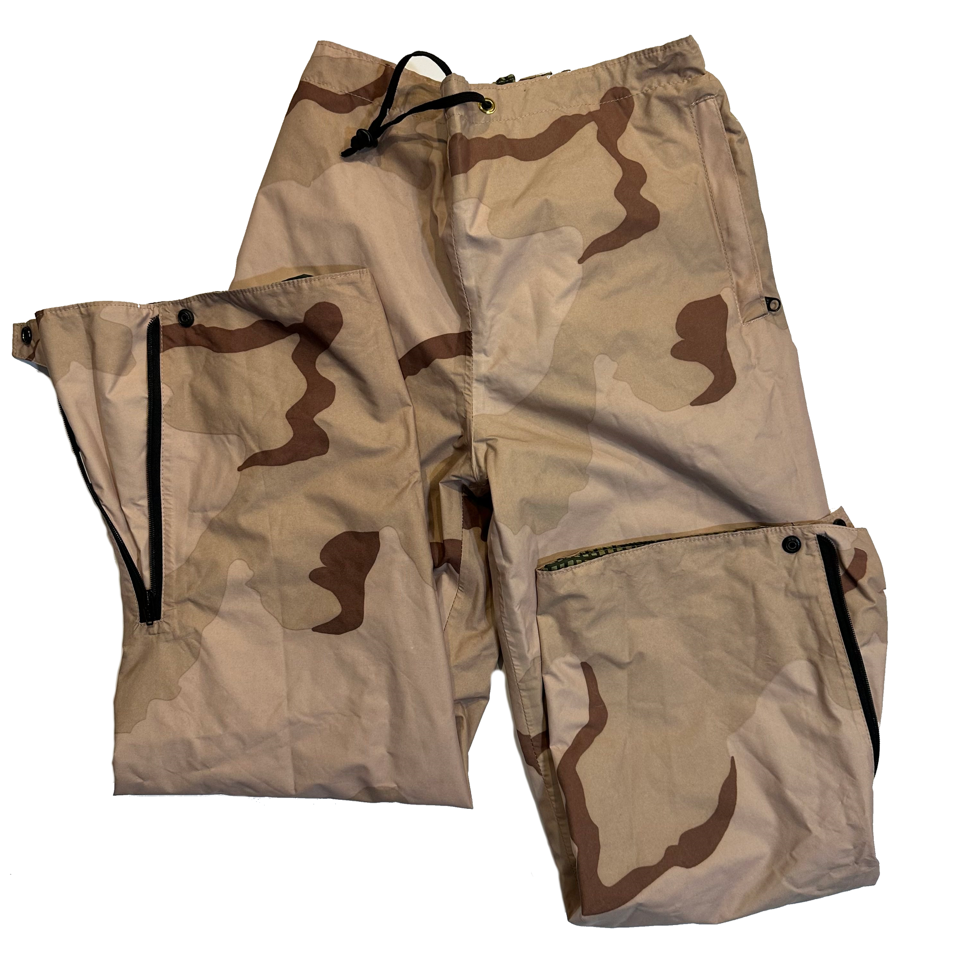 A pair of Reversible Desert Night Camo/3 Color Desert Gore-Tex Pants from Six Gun Surplus lying on a flat surface. The pants showcase a mix of beige, brown, and tan patterns with multiple pockets and zippers. Made from Taslite Nylon with DWR treatment, the fabric looks lightweight yet durable, ideal for outdoor activities. The drawstring waistband is also visible.