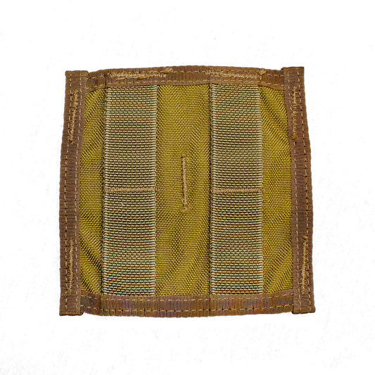 A Six Gun Surplus MOLLE Horizontal Adapter, a square piece of yellow fabric with brown edges and two vertical strips of brown and green material sewn onto it, creating durable loops. The fabric is textured, and the stitching is visible around the edges and strips, making it a versatile addition for customized storage solutions.