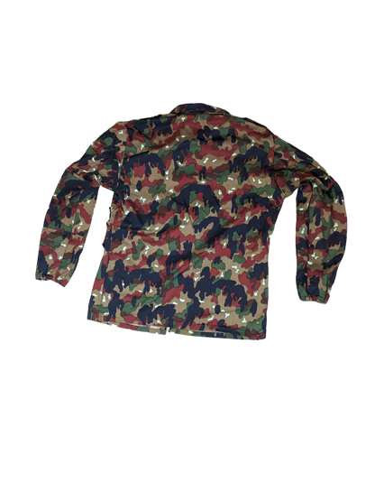 A back view of a durable, long-sleeved, button-up Swiss M83 Camo Field Shirt from Six Gun Surplus featuring a multicolored camouflage pattern in shades of green, brown, black, and beige. The shirt is laid flat against a black background.